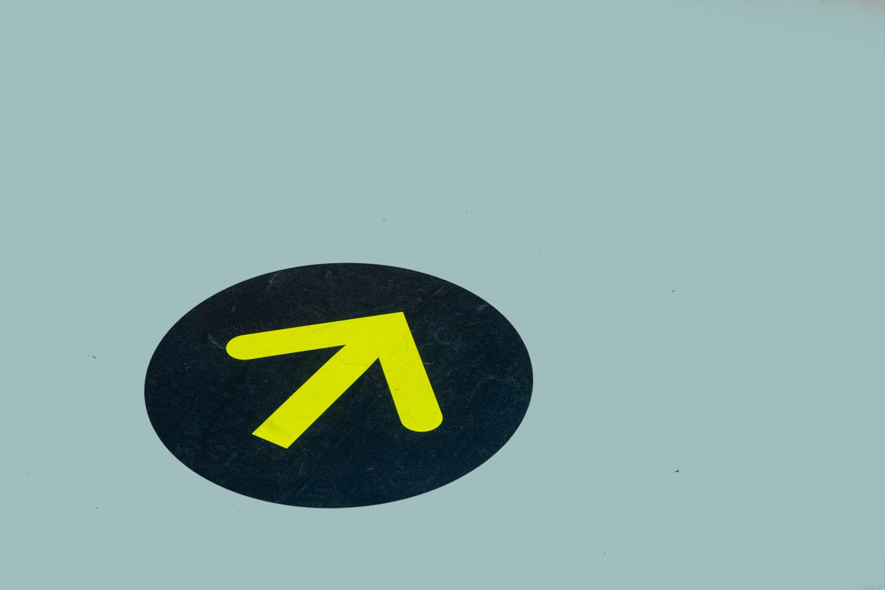 services-04 Minimalist image of a yellow arrow on a blue floor indicating direction, ideal for navigation themes.