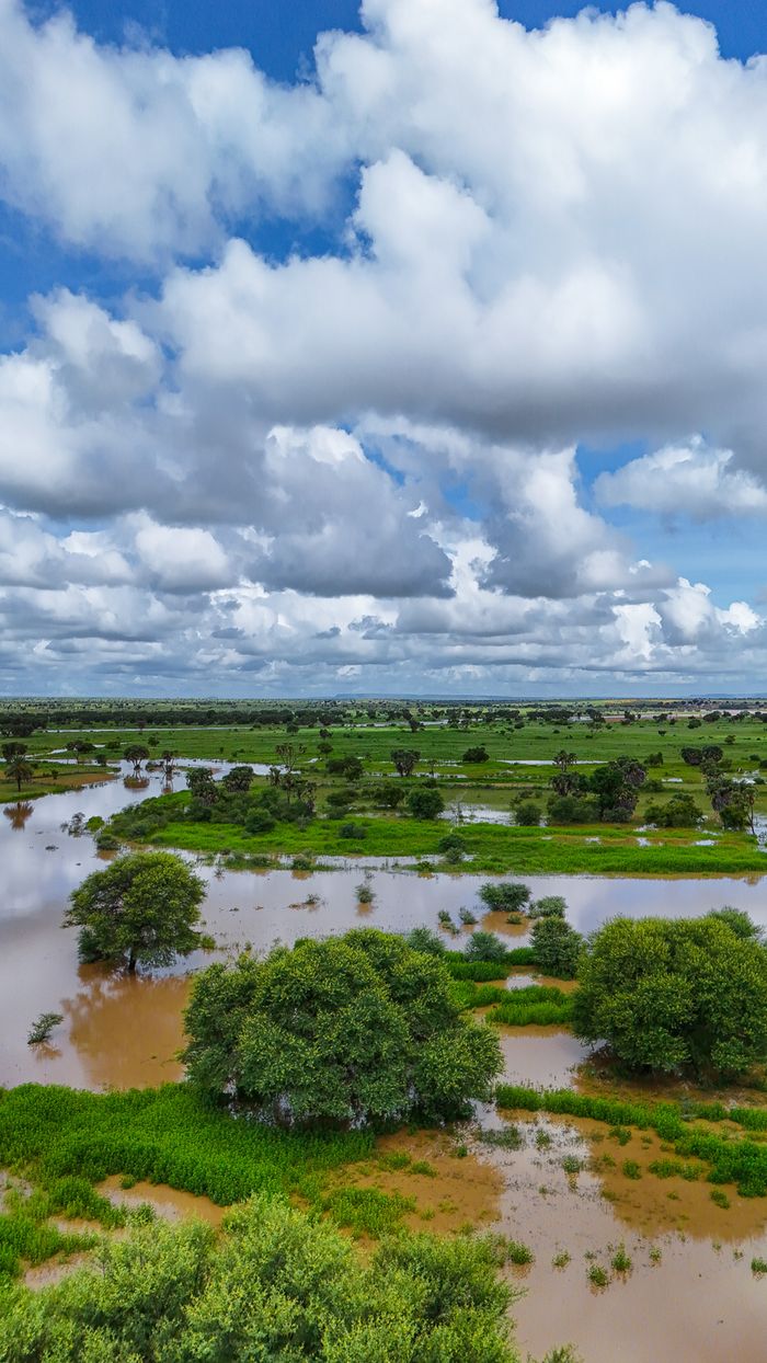 hero-img-02 High-angle aerial shot of a flooded landscape with lush greenery under a bright cloudy sky.