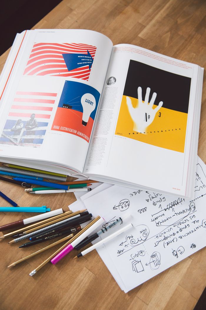 The Art of Drawing Readers In: Your attractive post title goes here Top view of a creative desk setup with an open book and design sketches, perfect for inspiration.