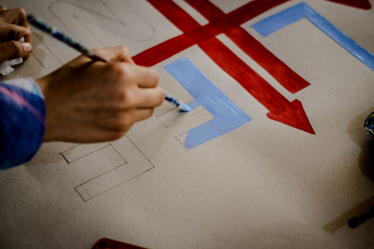 services-img Artistic close-up of a hand painting colorful arrows on paper, showcasing creativity and craftsmanship.